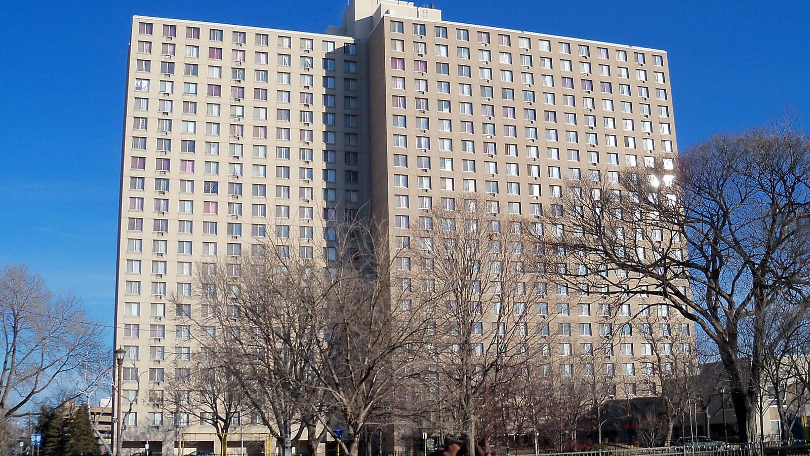 Pale apartment tower with bare trees in front