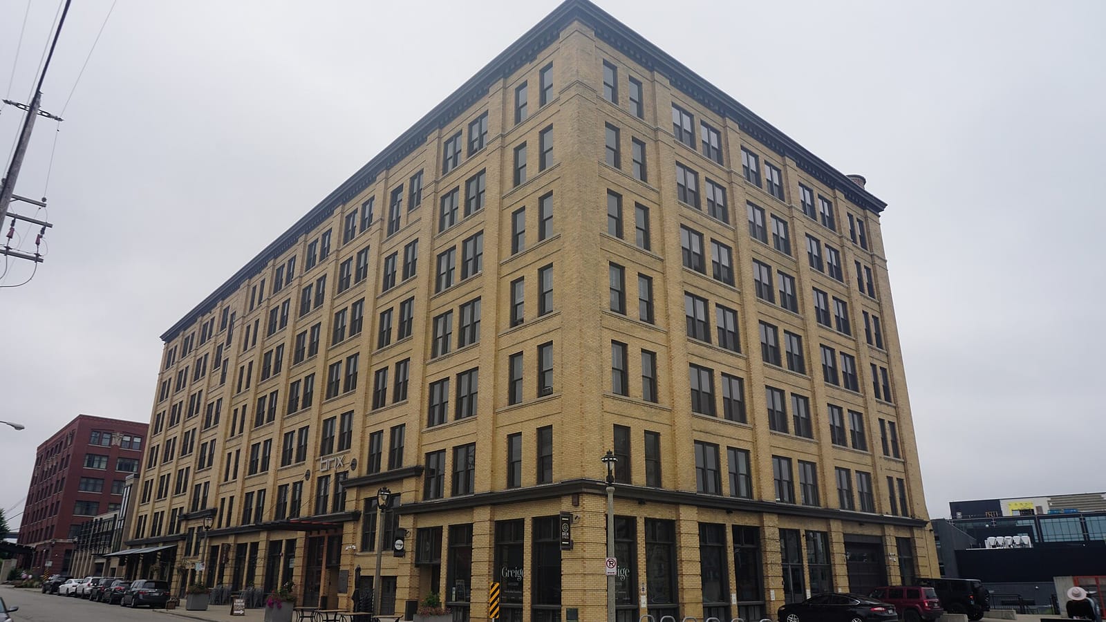 Tall tan brick apartment building with ground-floor storefronts