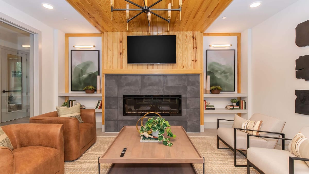 Lounge with a wall-mounted television over a tiled fireplace, a wood-paneled ceiling, leather chairs, a sofa and a coffee table