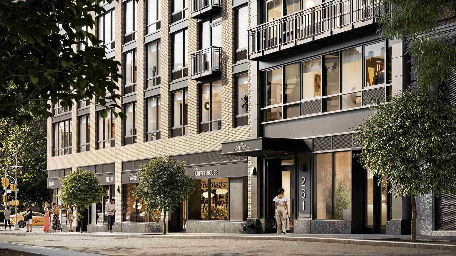 Rendering of the building's entrance on West 24th Street, with a dark canopy reading The Andrea, the house number 261 beside a glass door, light brick upper floors with small balconies, ground-floor shops and a woman walking to the door
