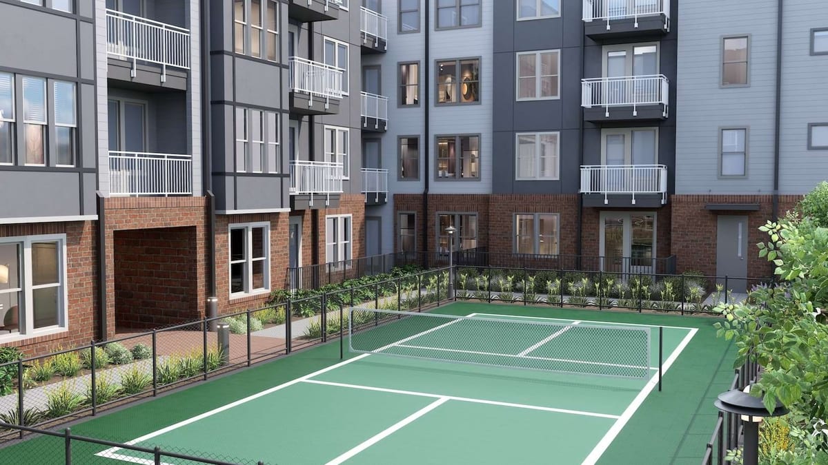 Rendering of a green pickleball court in a courtyard beside brick and grey apartment buildings with balconies