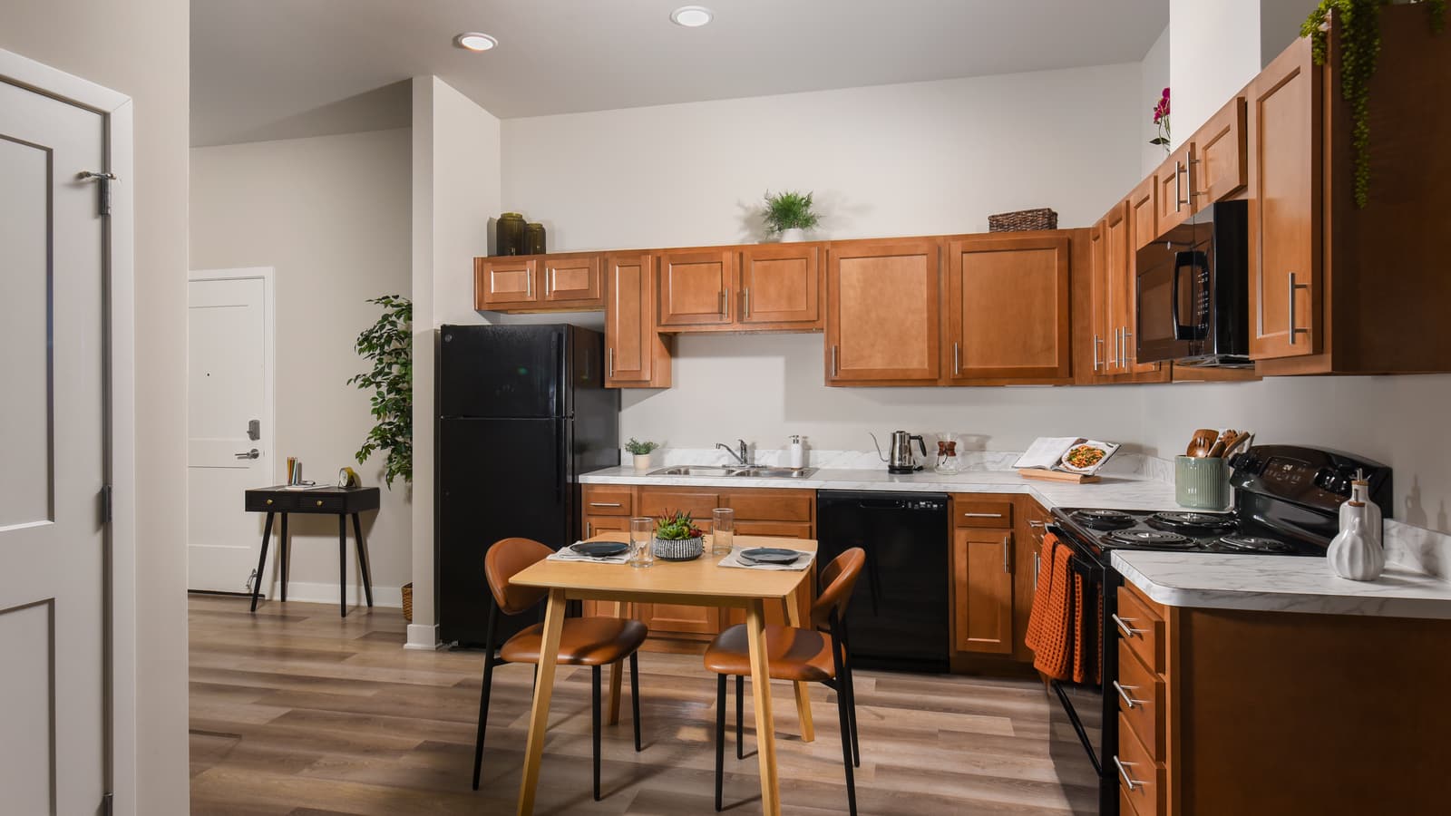 A kitchen with wood cabinets, a black refrigerator, range, microwave and dishwasher, and a small table with two chairs
