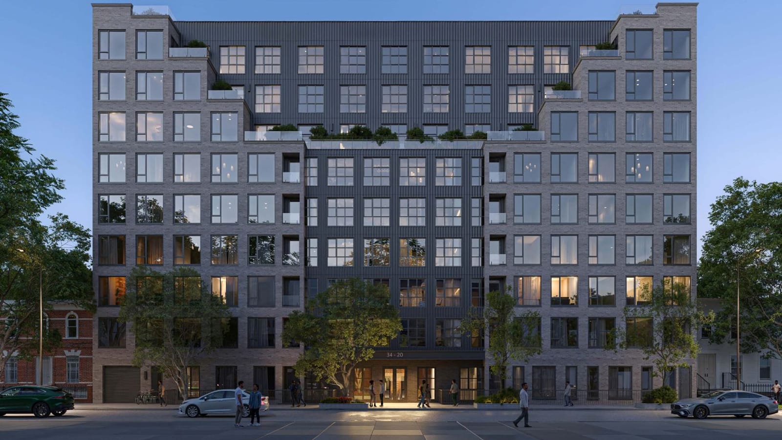 Rendering at dusk of a nine-story apartment building of gray brick with a dark metal-panel center section, upper-floor setbacks with planted terraces and glass railings, a lit entrance under the number 34-20, street trees, a few small figures on the sidewalk and parked cars, with older brick houses at each side