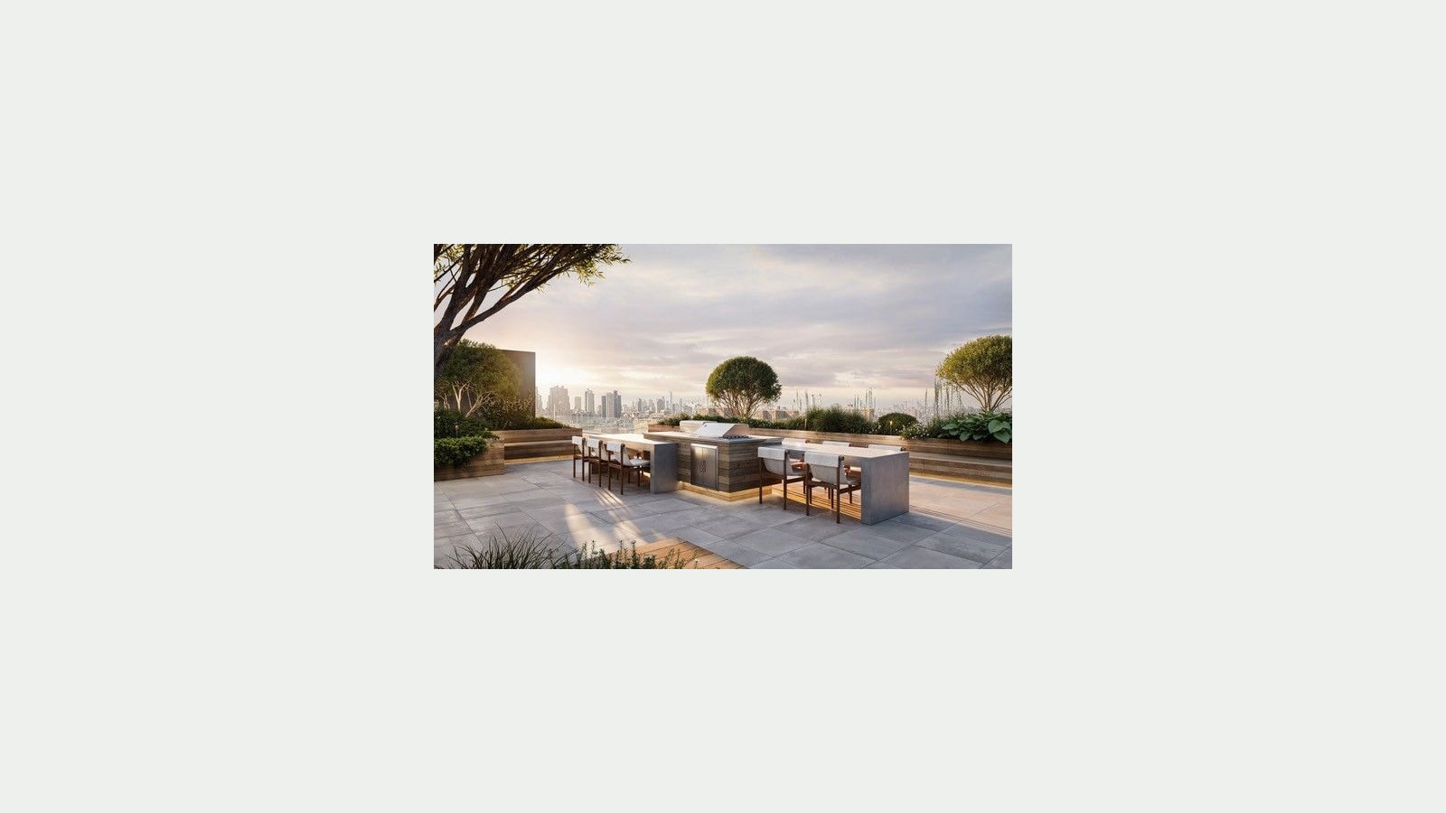Rendering of a roof terrace at sunset with a long stone counter holding a built-in grill, two dining tables with wooden chairs, planters with shrubs and small trees, gray paving stones and a city skyline in the distance