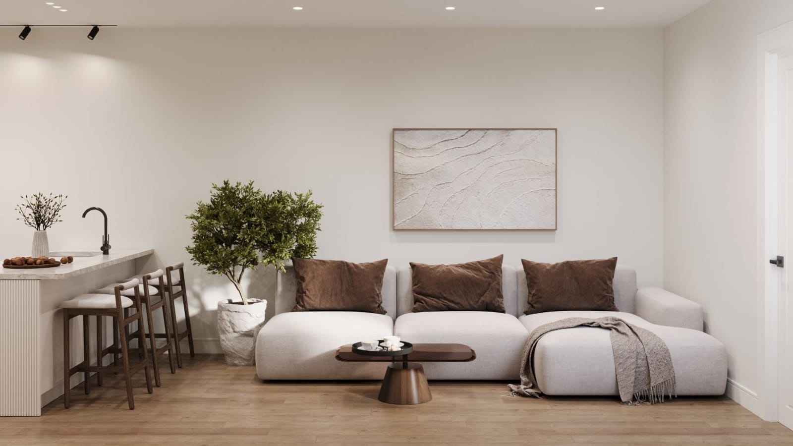 Rendering of a furnished living room with a light gray sectional sofa, brown cushions, a small wooden coffee table, a potted tree, light wood floors and a kitchen counter with three stools at left