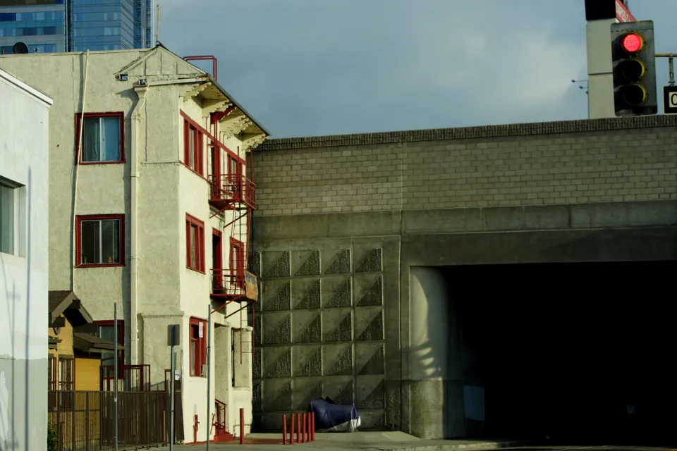 Older Los Angeles apartment building with a projecting bay beside a commercial facade