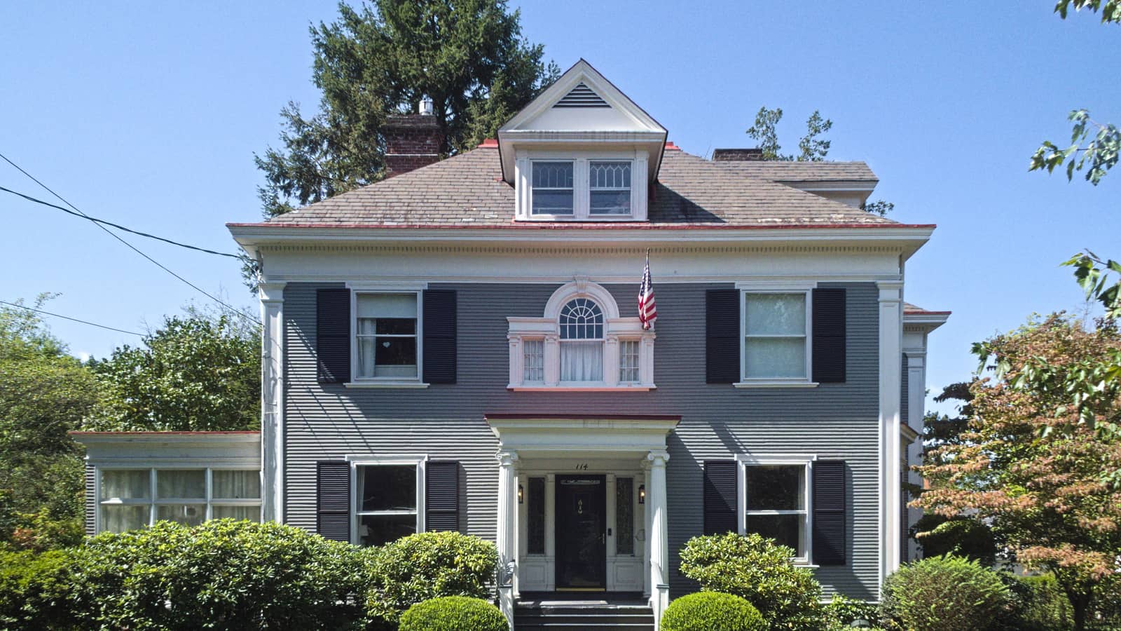 A two-story house with a porch, shingled roof and mature trees in Sewickley, Pennsylvania.