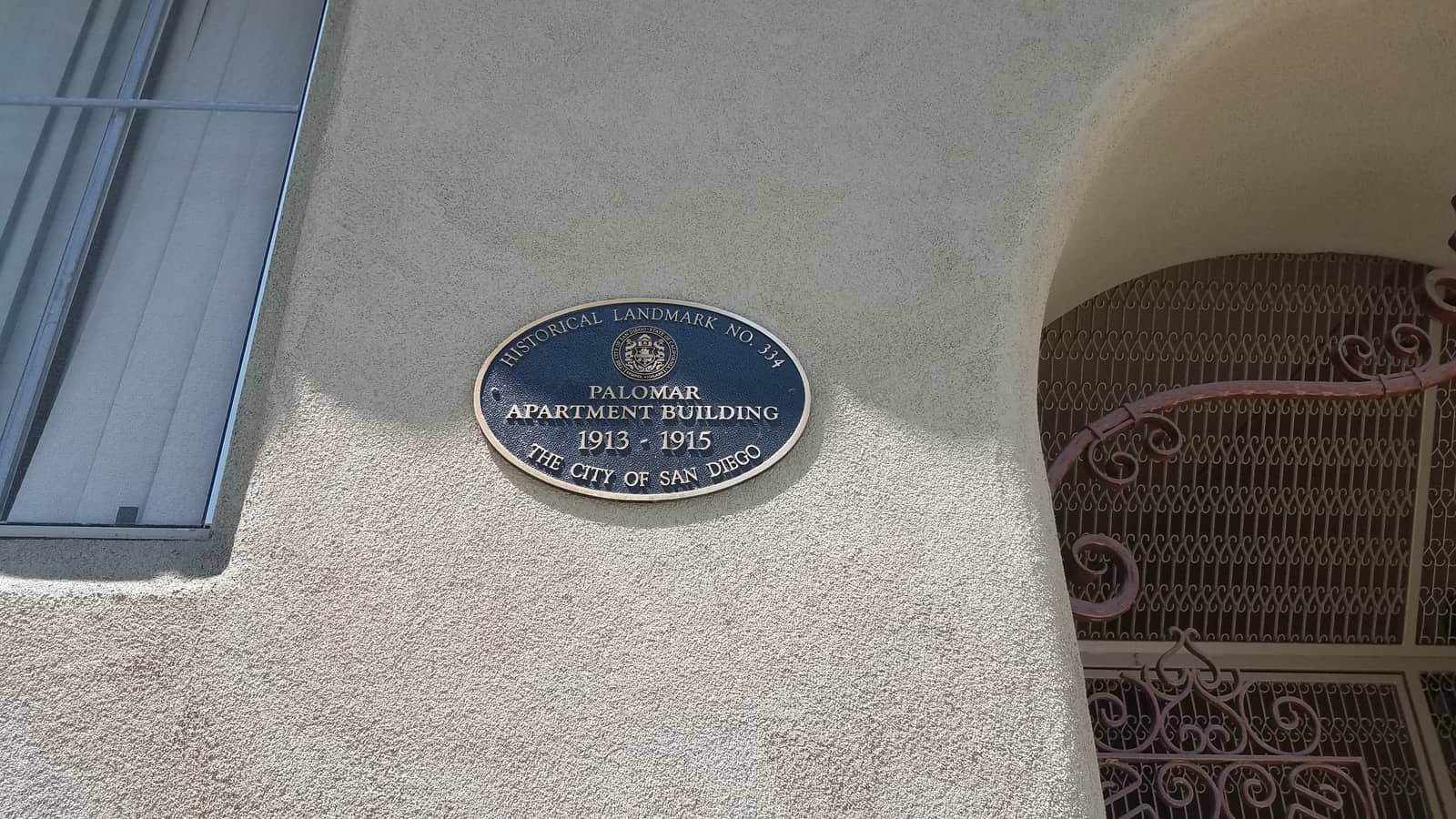 Historical landmark plaque on the stucco wall of the Palomar Apartment Building in San Diego.