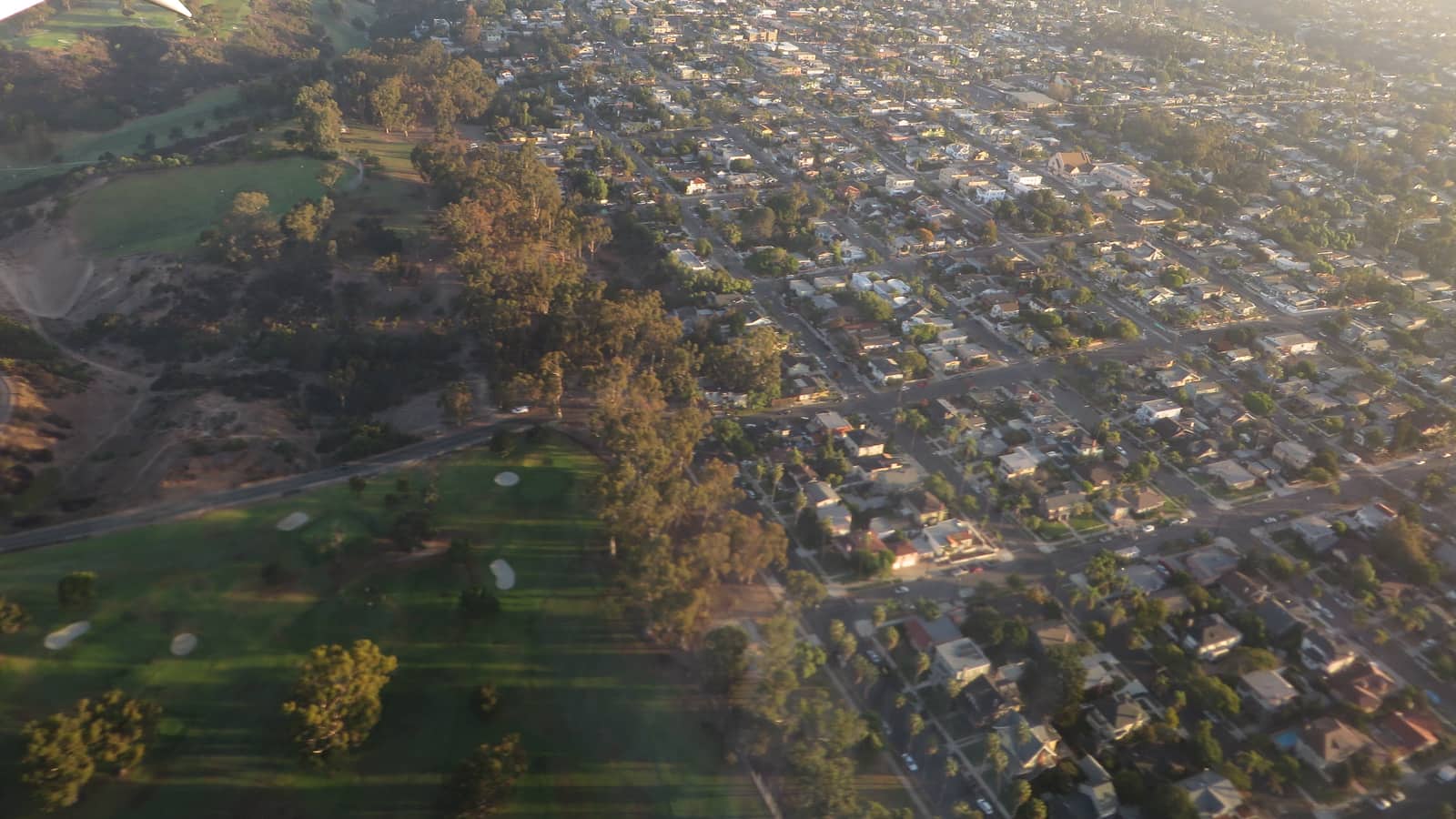 Aerial view of low-rise blocks beside a green canyon in South Park, San Diego.
