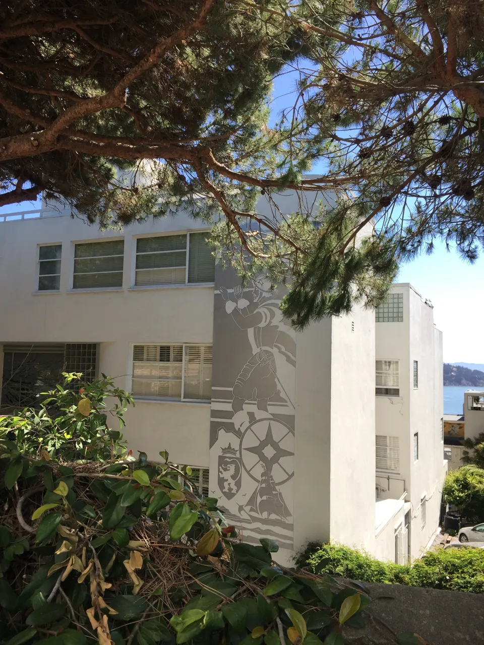 Exterior balconies and artwork partly framed by trees at the Malloch Building in San Francisco.