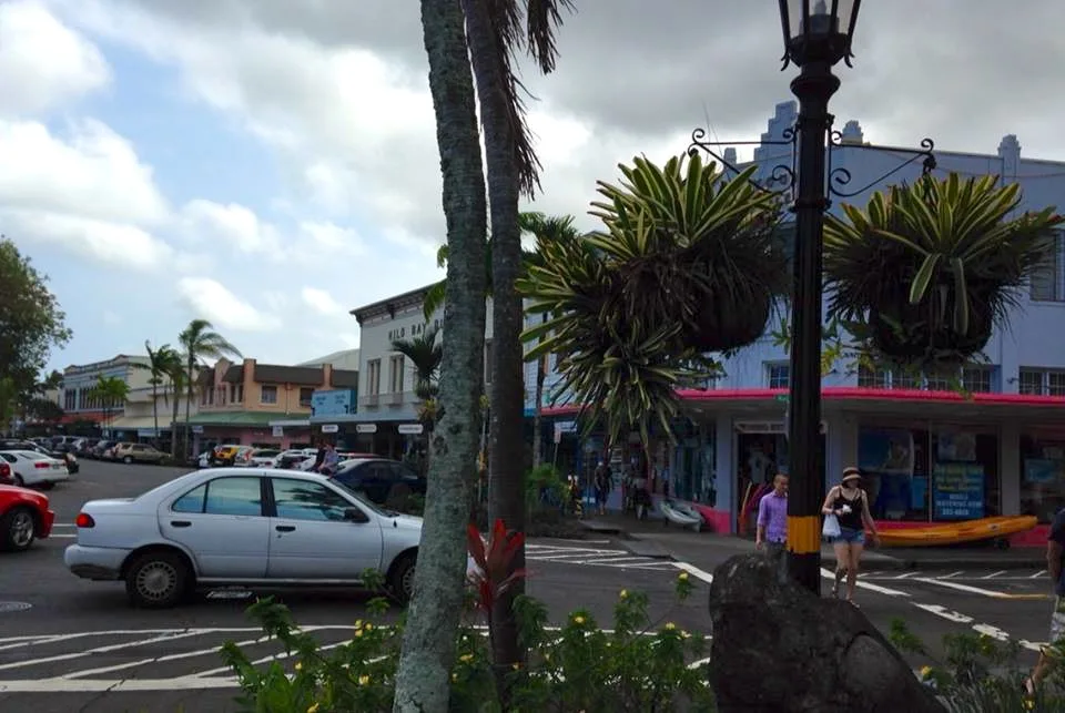 Low-rise storefronts, palms and parked cars in downtown Hilo