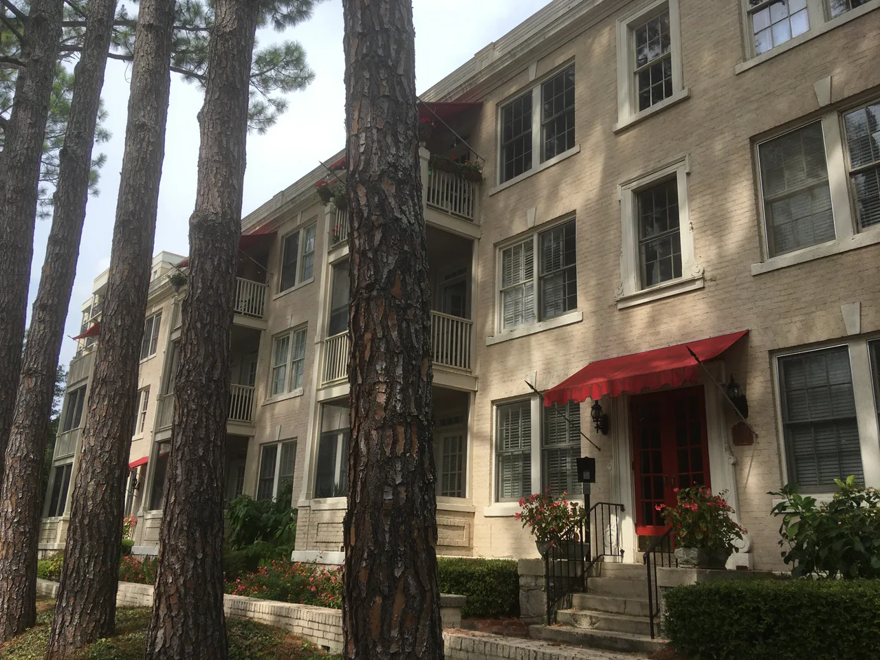 Low-rise pale brick apartments with balconies and red awnings at Peachtree Commons in Atlanta