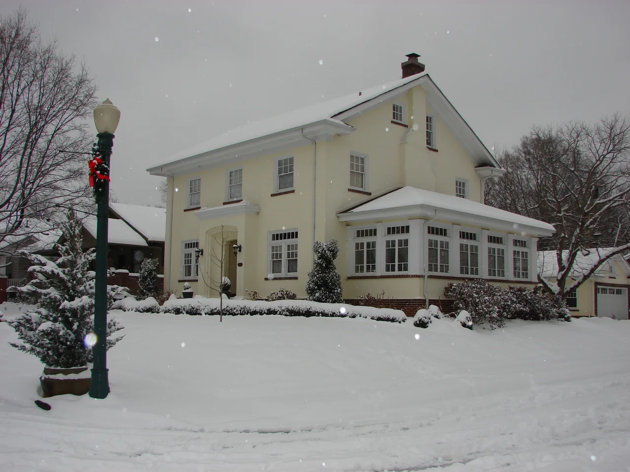 Light-colored two-story house with a broad porch in snowy Ferger Place, Chattanooga