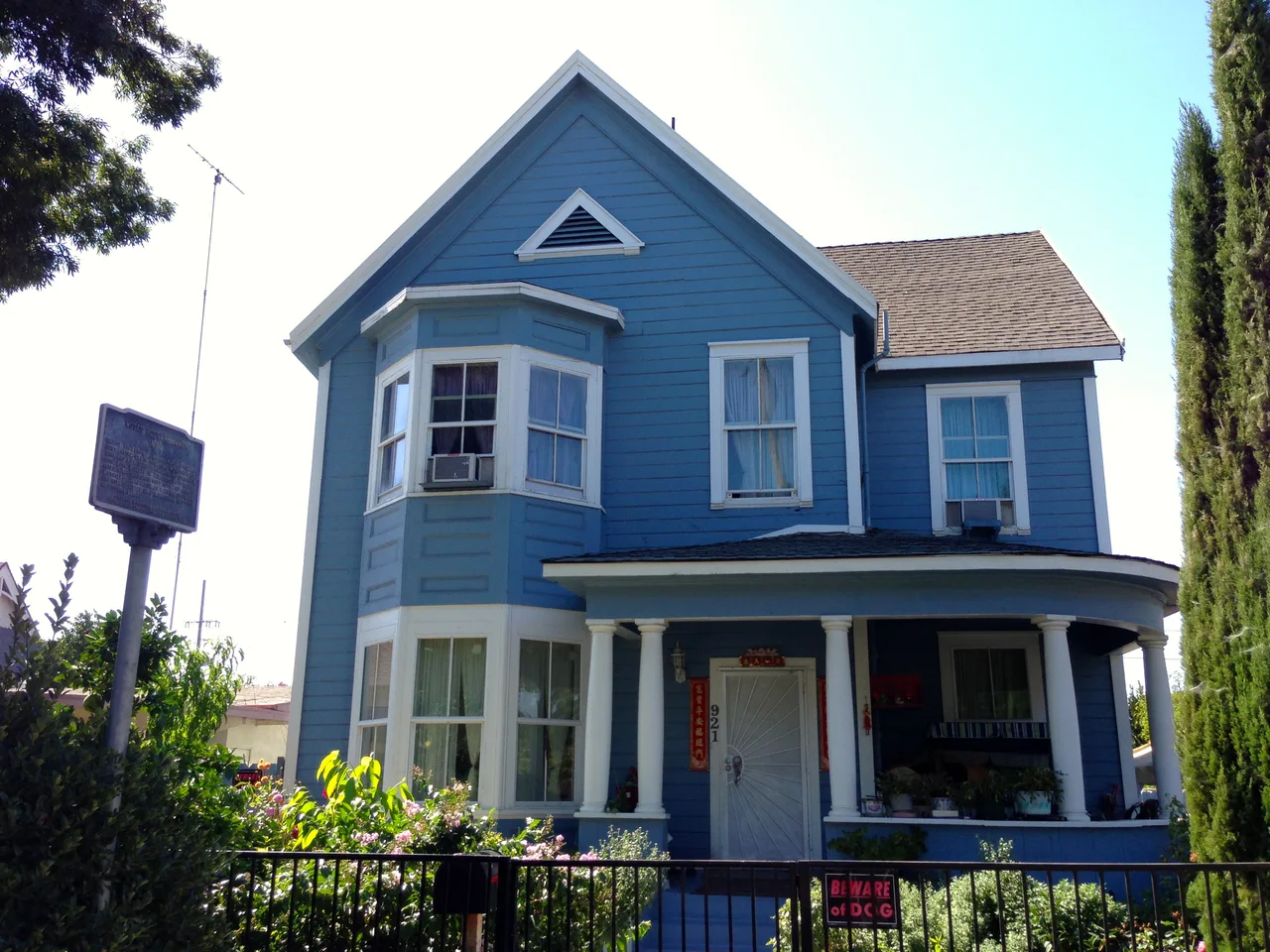 Blue wooden Moses Rodgers House with a front porch and projecting window bay in Stockton