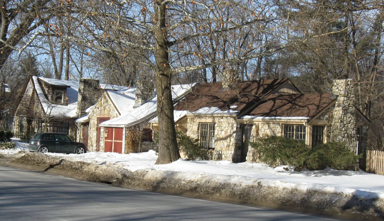 Stone Moffitt cottages beside a snowy Iowa City street and mature trees