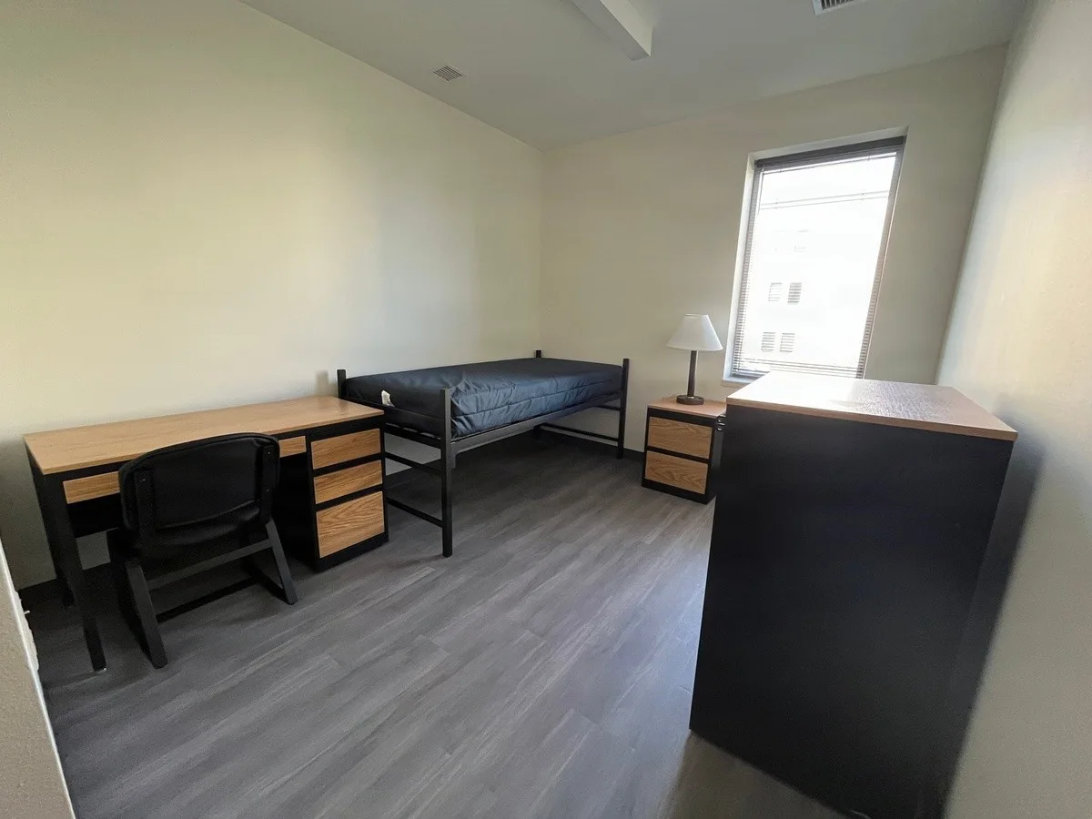 Unoccupied furnished bedroom with bed, desk, chair and storage in Fort Hood Barrack 101