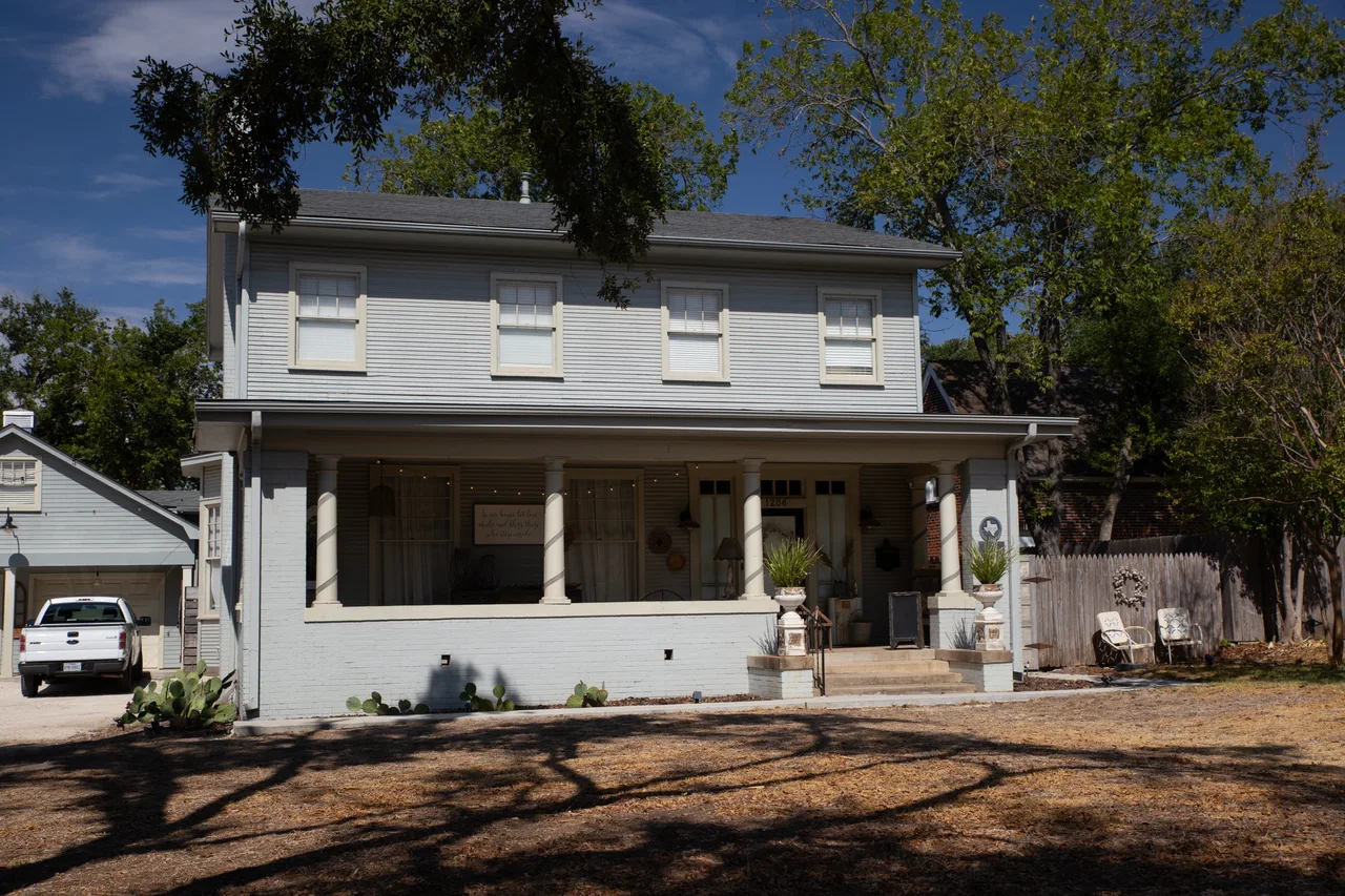 White two-story C. L. Walker House with a broad porch beneath trees in Temple, Texas