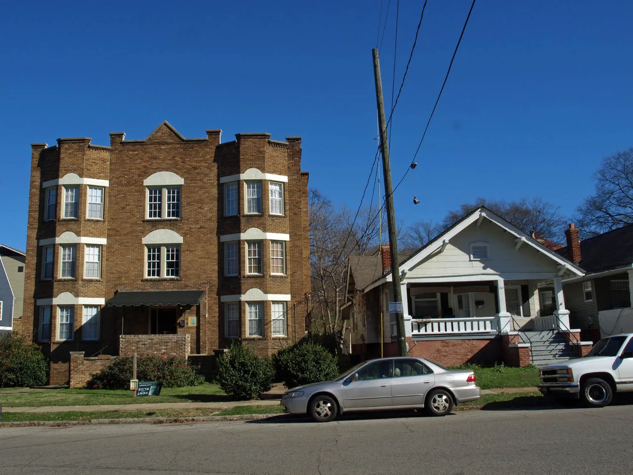 Three-story brick apartment building beside a porch-front bungalow on 14th Street South in Birmingham
