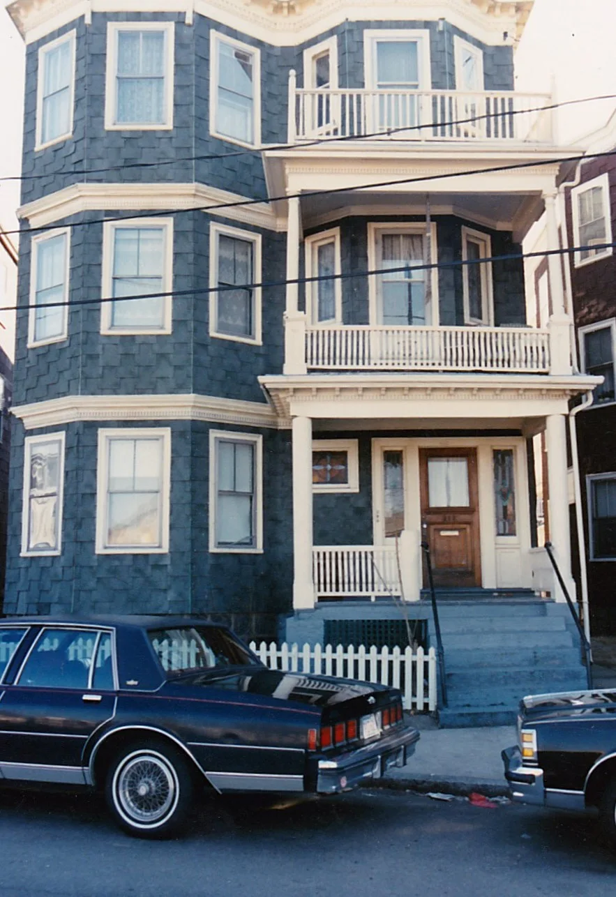 Stacked porches and projecting window bays on a blue triple-decker in Dorchester, Boston