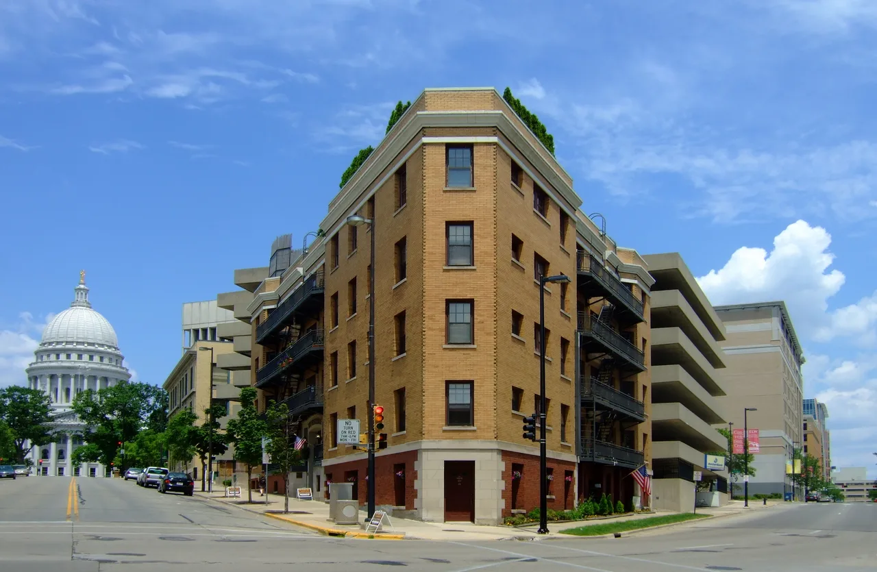 Baskerville brick apartment building at a Madison street corner with the Wisconsin Capitol behind it