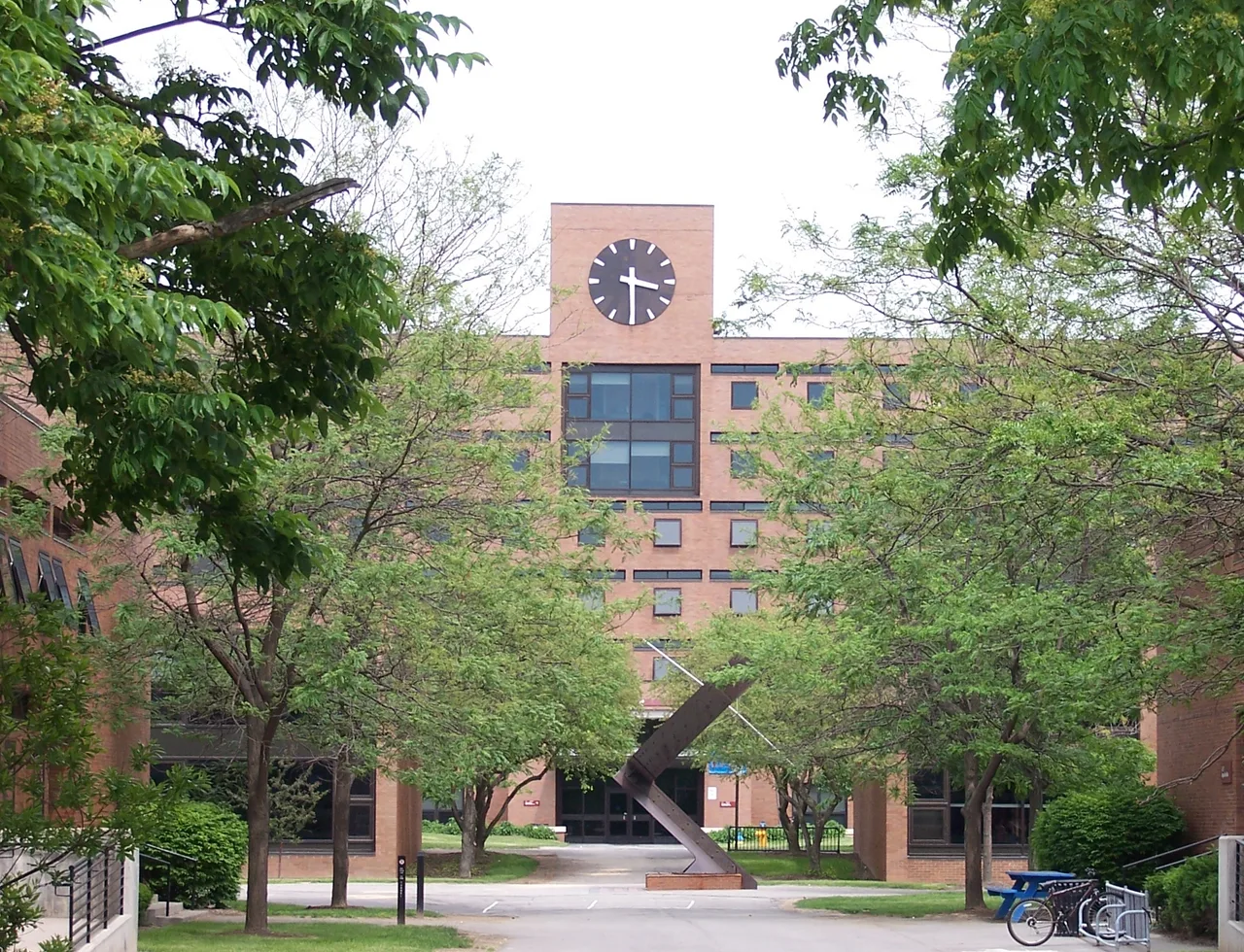 Kate Gleason Hall at RIT with a sundial sculpture, trees and a clock above the entrance