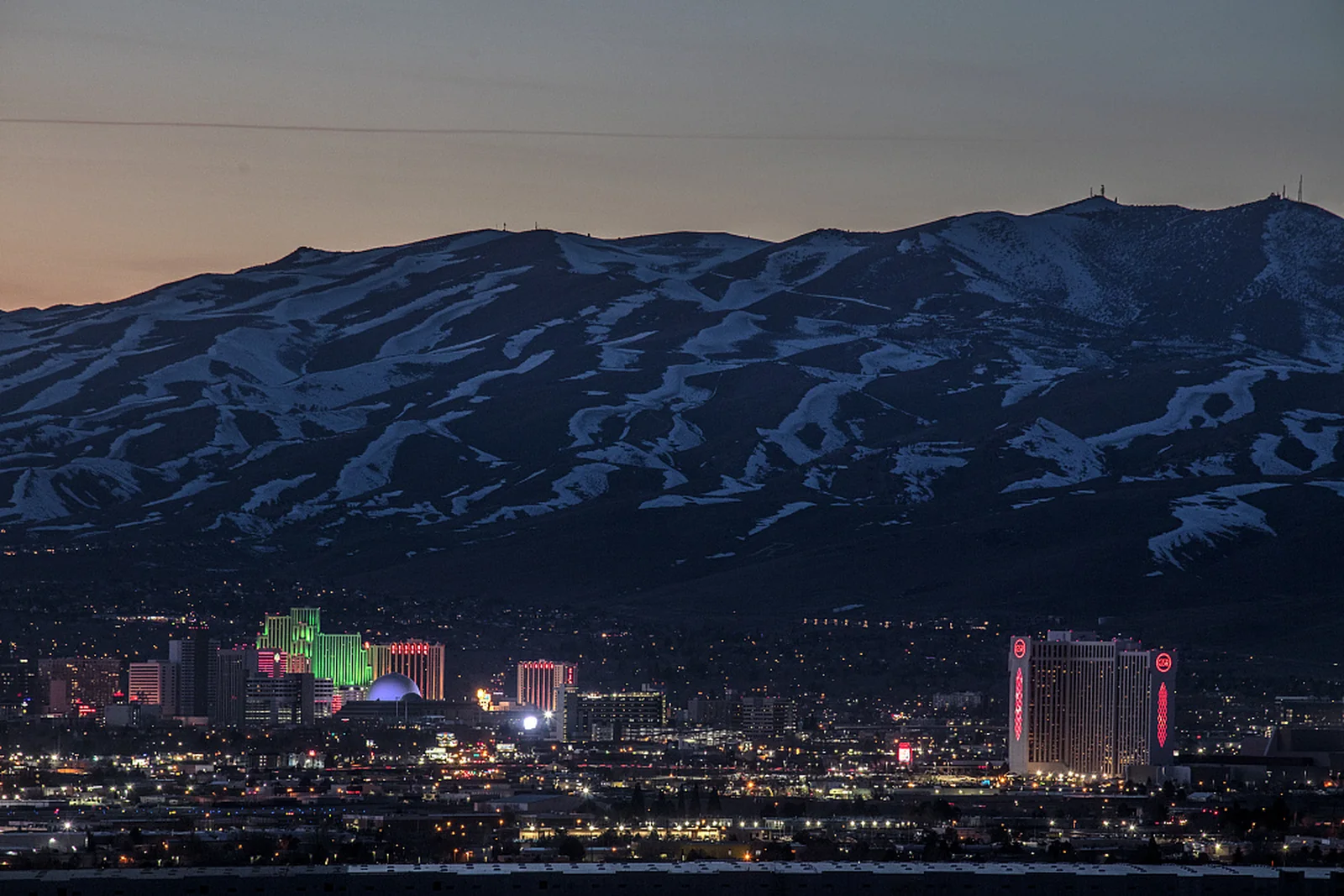 Reno buildings at dusk beneath snow-covered mountains