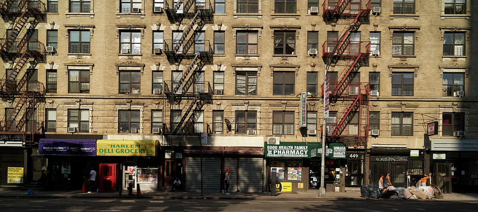 Harlem apartment facades above street-level shops and fire escapes