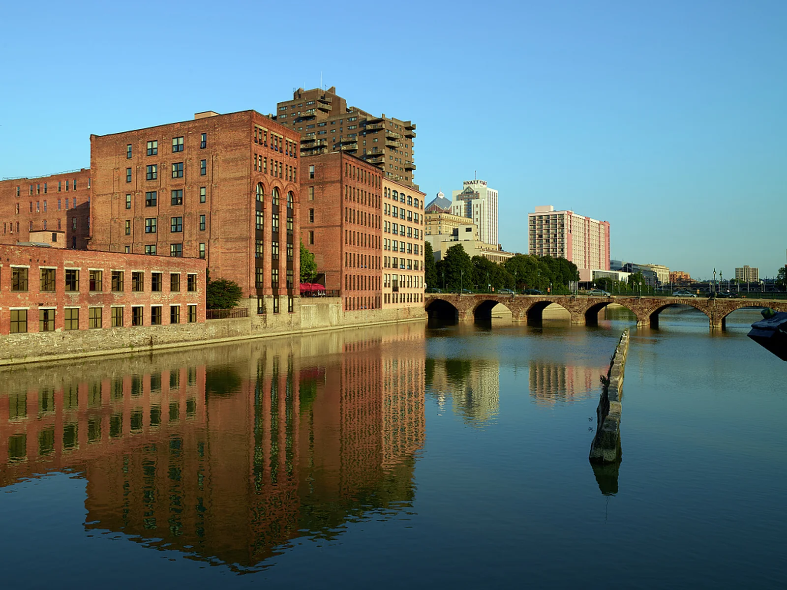 Brick buildings and downtown towers reflected in the Genesee River in Rochester